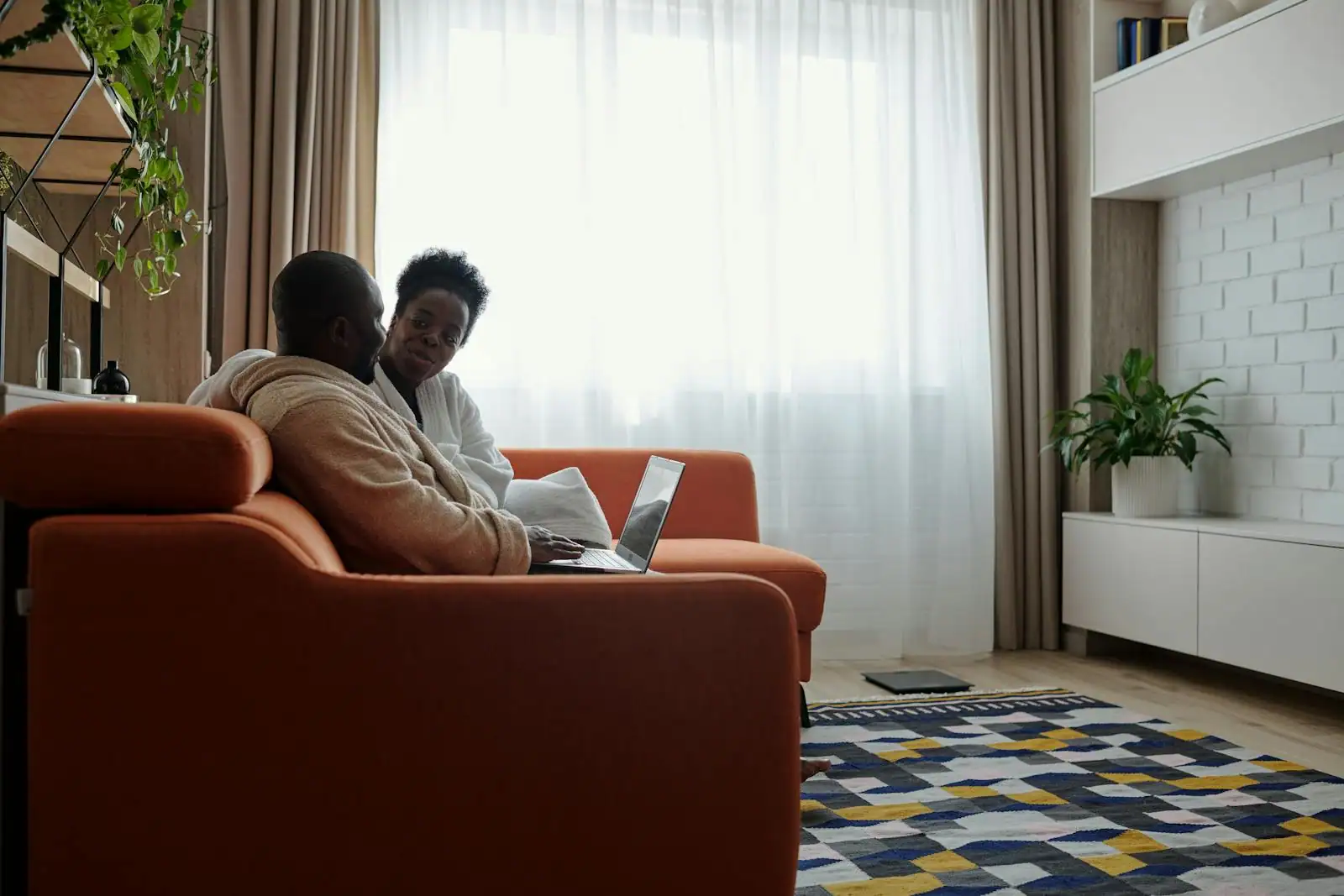 Couple installé sur un canapé en lumière naturelle, conversation calme et attentive