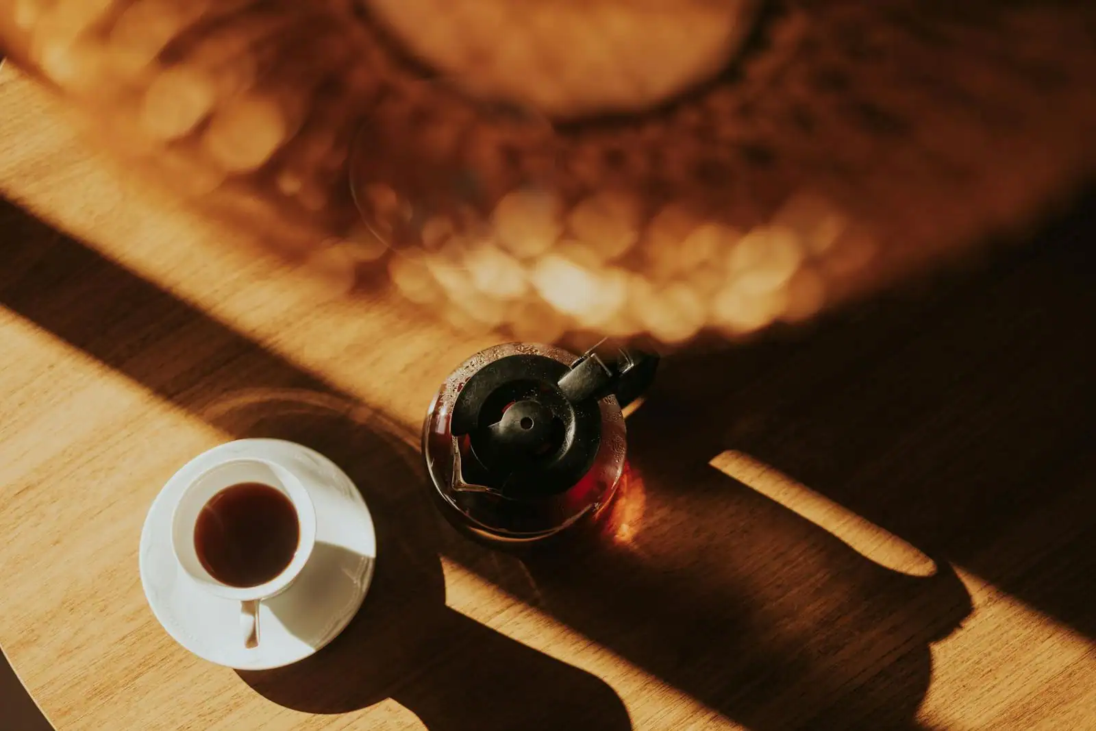 Tasse de café fumante près d'une fenêtre ouverte sur les toits, lumière du matin sur une table en bois