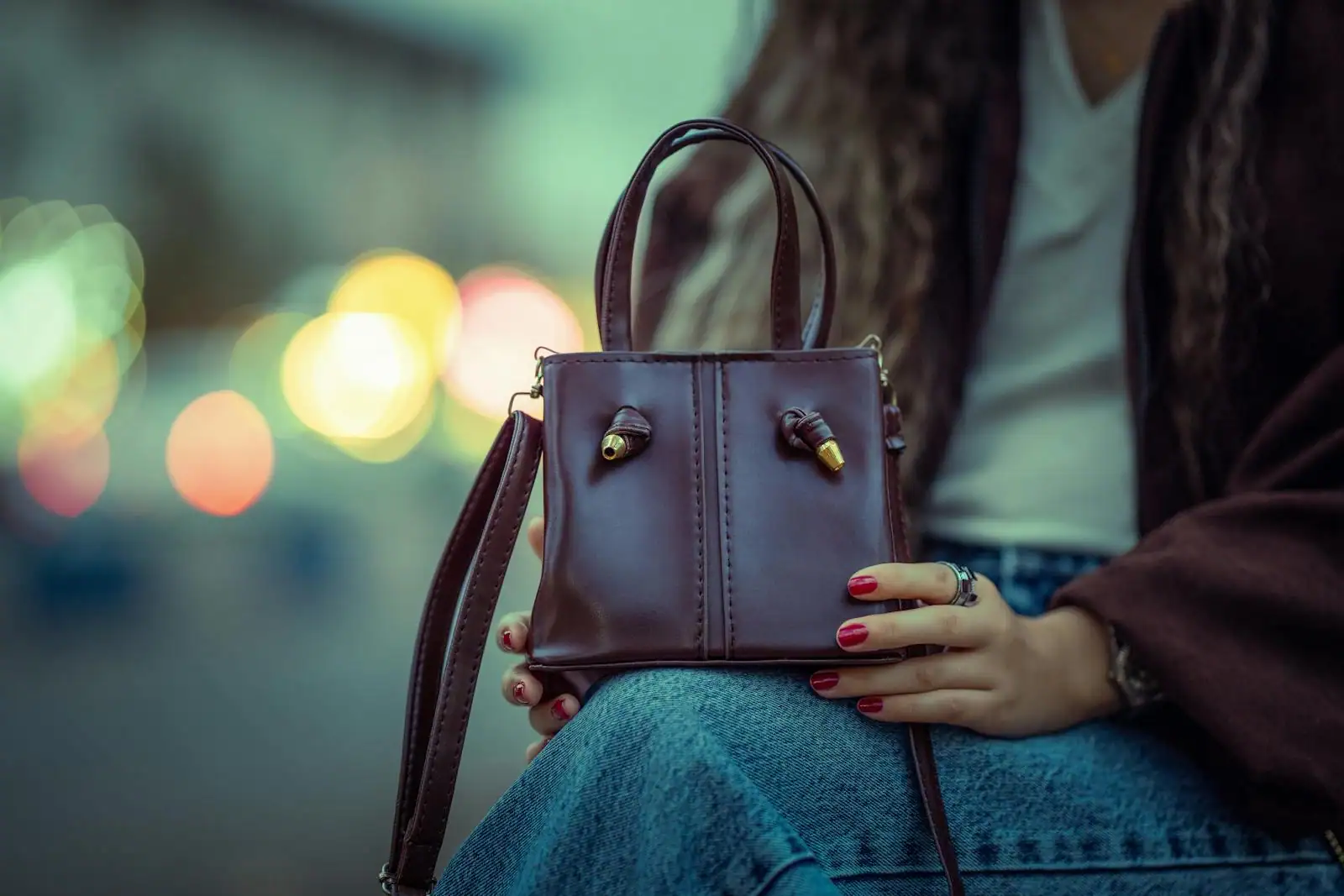 Sac à main bandoulière en cuir porté en travers du buste, détail couture et anse longue, scène urbaine