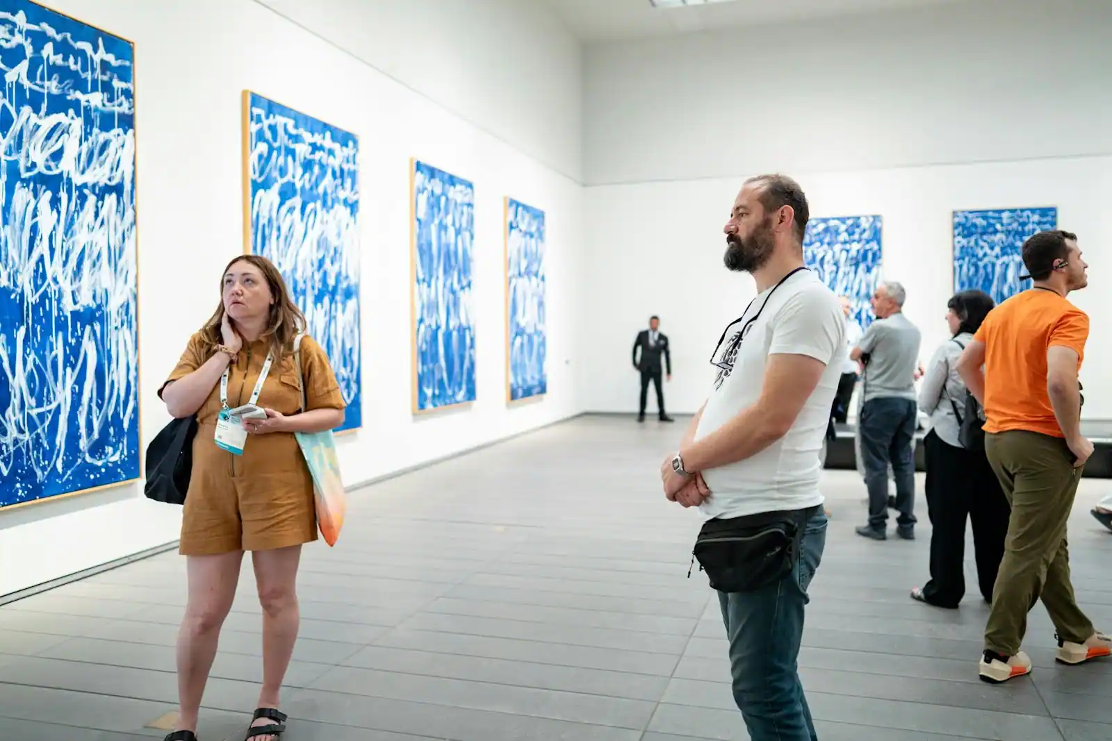 Visiteurs déambulant dans la grande galerie d'un musée d'art, lumière zénithale et œuvres en perspective