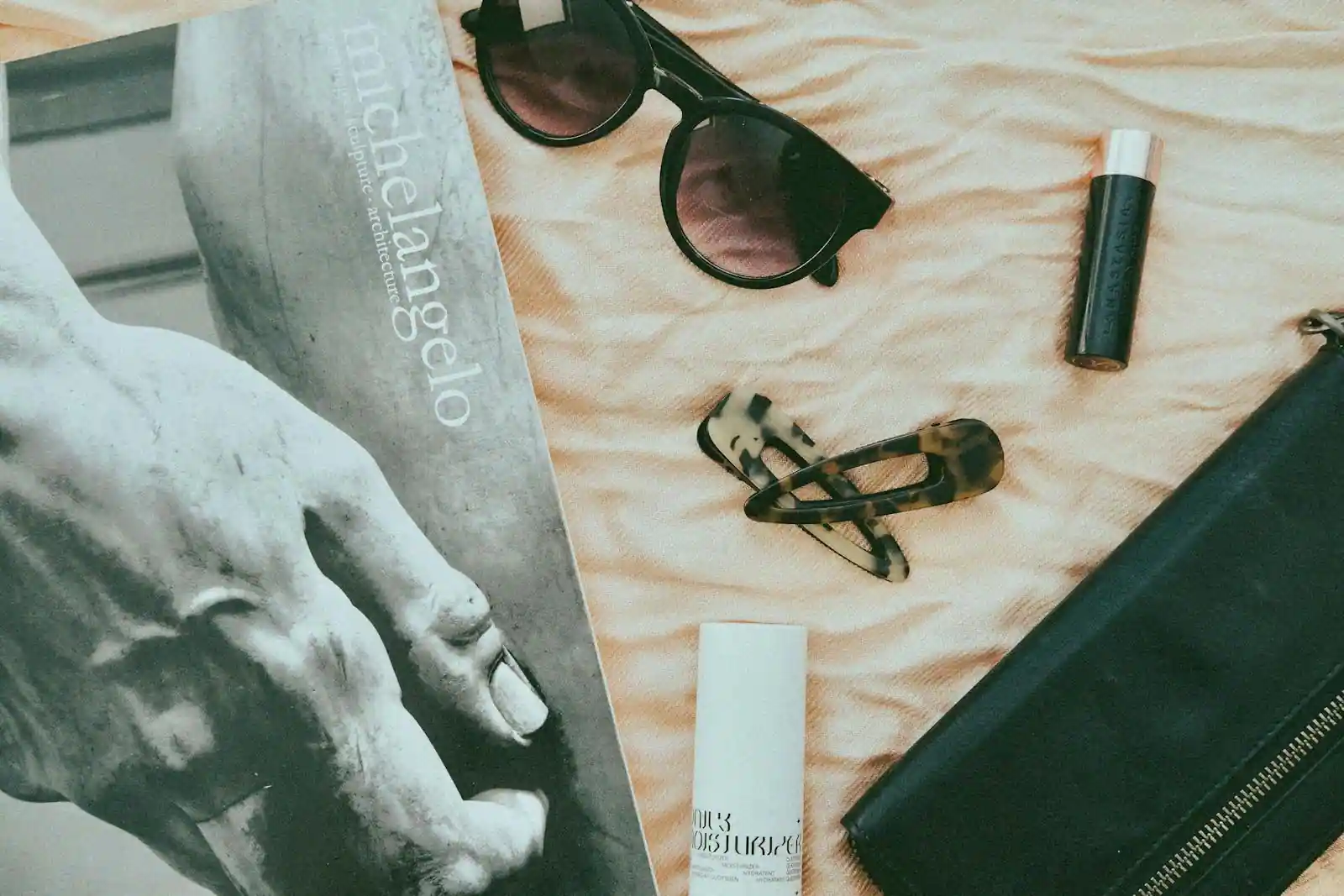 Composition à plat de magazines de mode, smartphone affichant une appli sociale et accessoires beige et crème, ambiance studio éditorial
