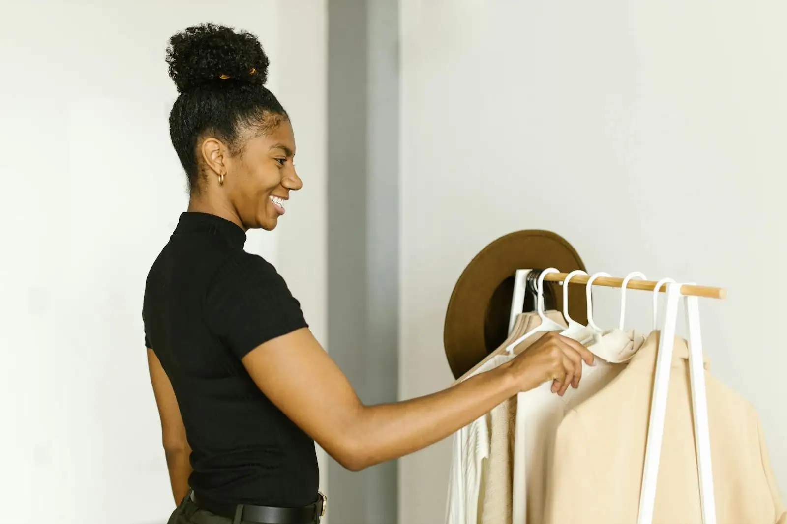 Portant de vêtements femme aux teintes neutres dans un dressing organisé, pièces structurantes mises en avant