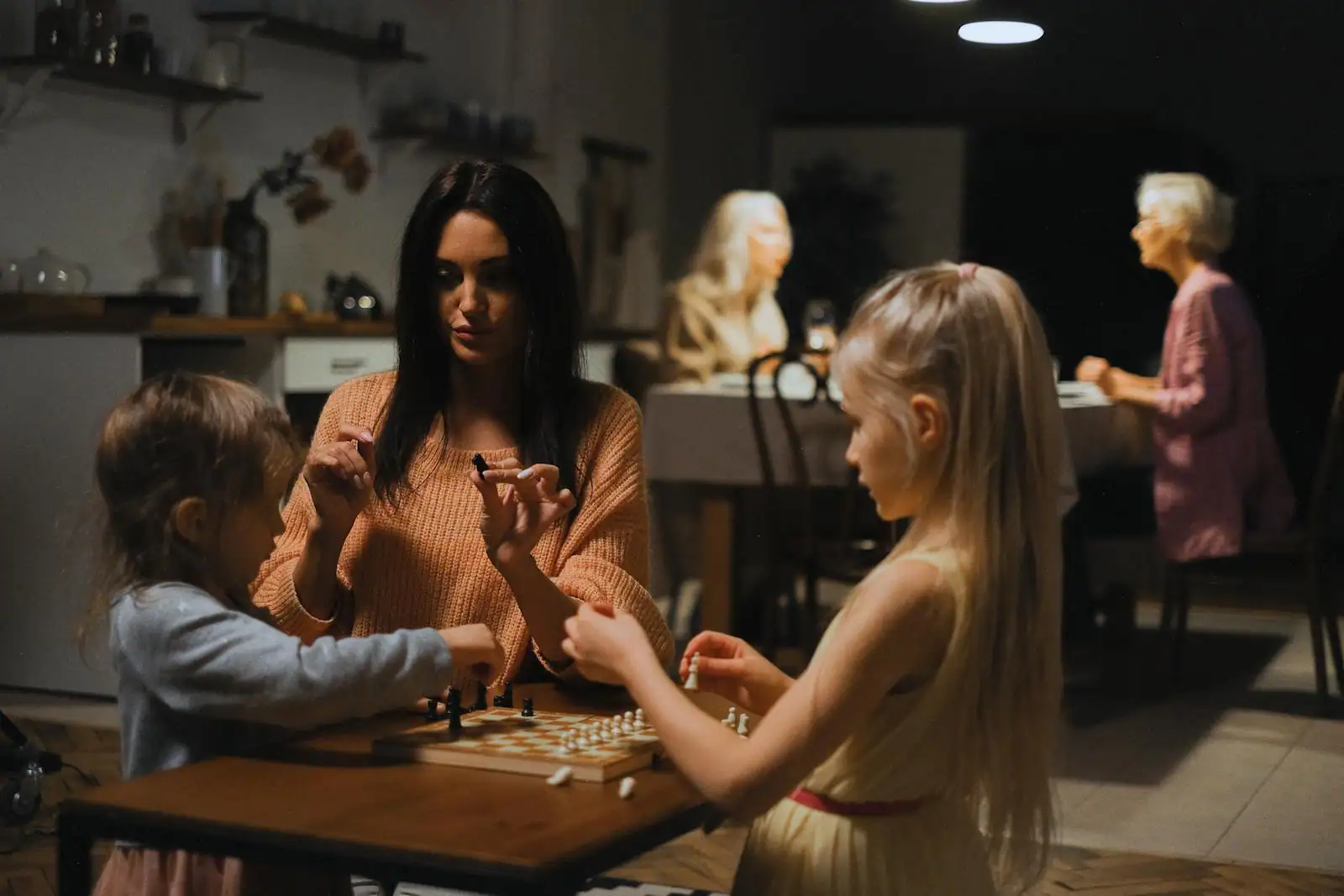 Une mère et ses enfants jouent à un jeu de société autour d'une table à la maison