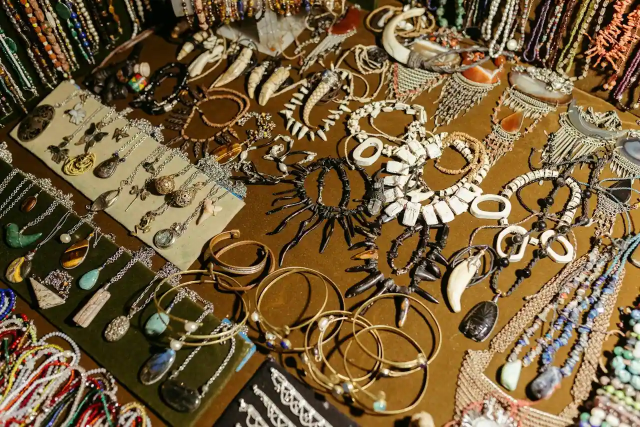 Bijoux fantaisie pour femme — créoles dorées, colliers fins et bracelets posés sur un tissu clair