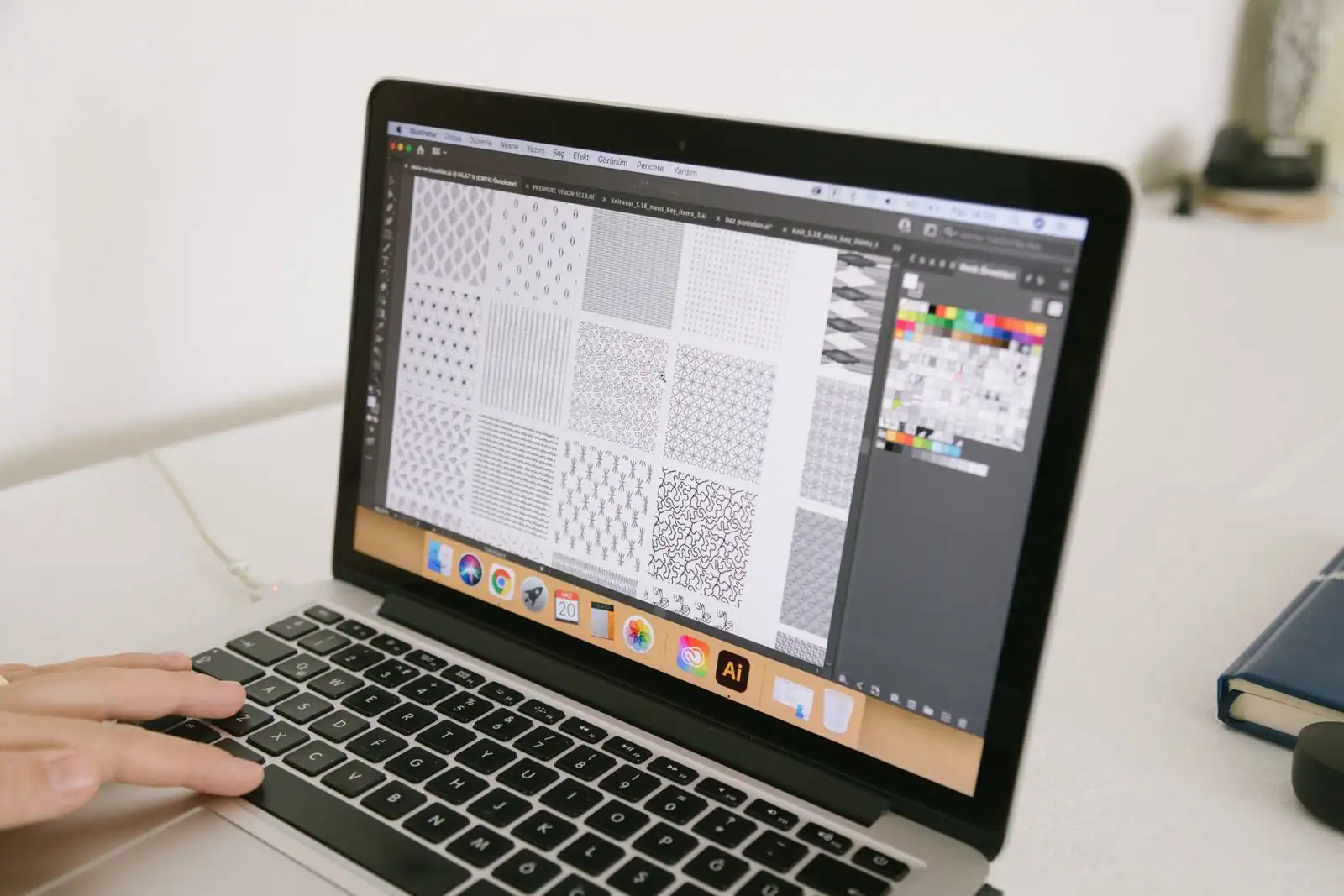 Personne concevant un design graphique à l'écran d'un ordinateur portable, logiciel de création ouvert.