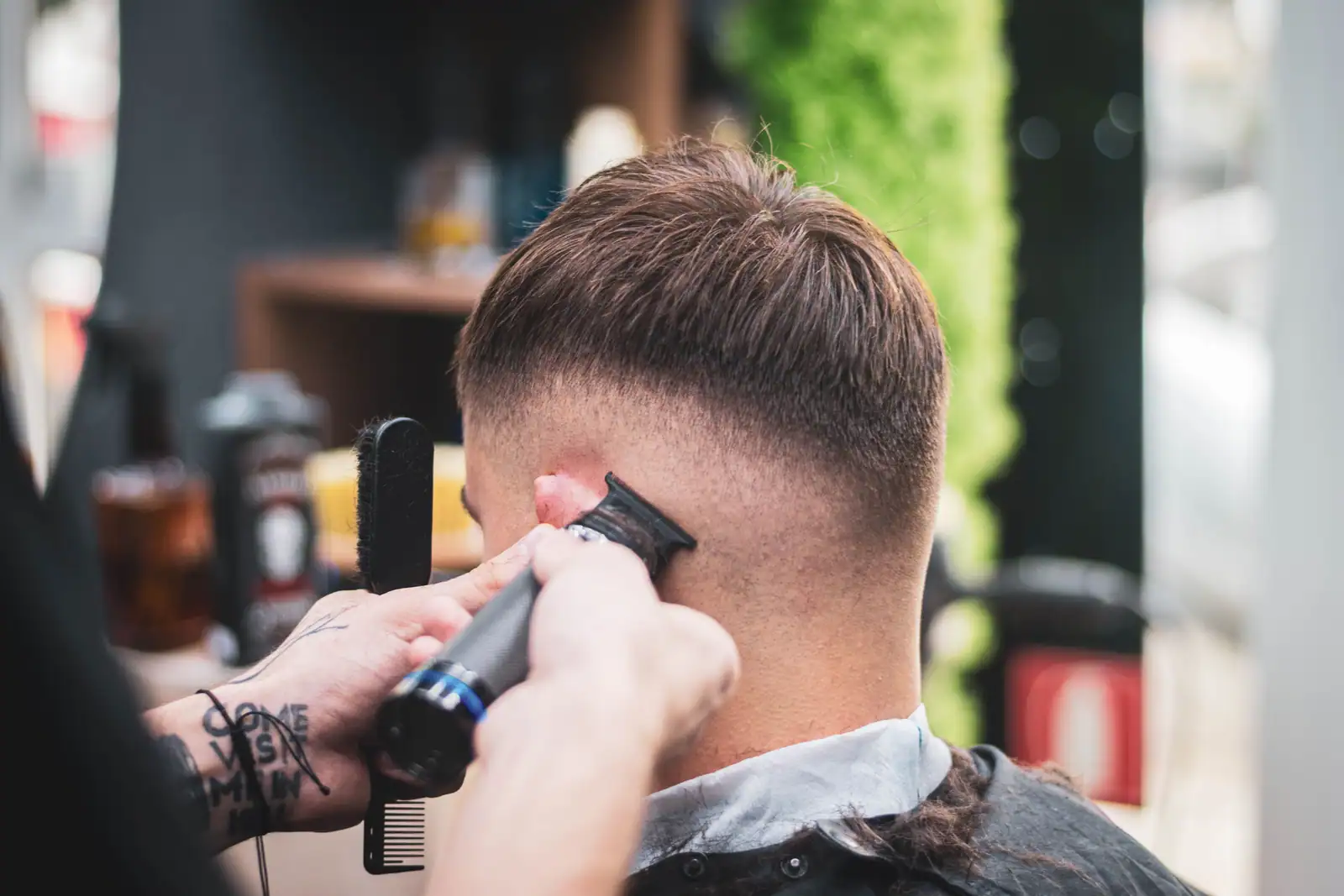 Dégradé réalisé à la tondeuse sur la nuque d'un homme, vue de dos dans un salon de barbier.
