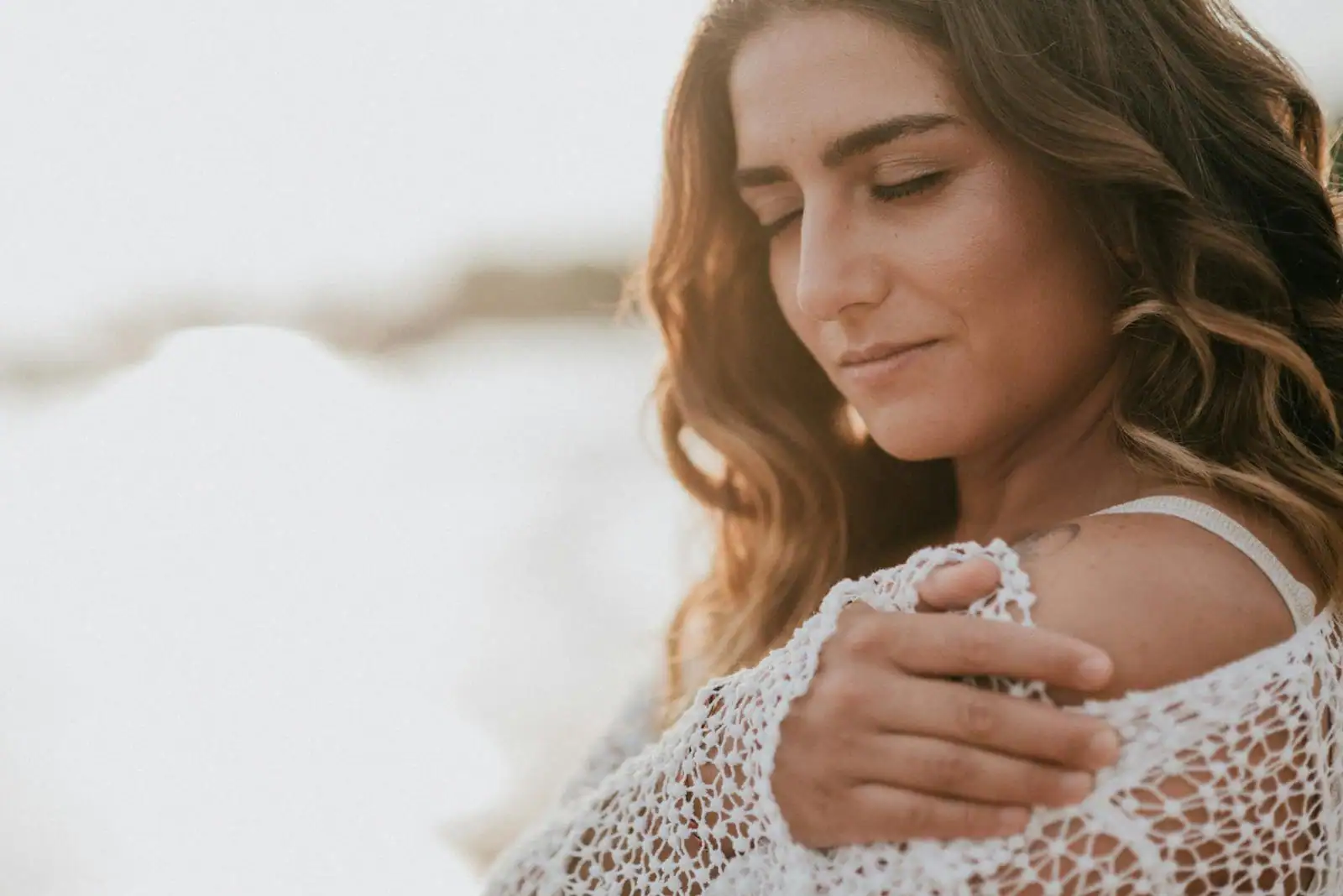 Une femme sereine, la main posée sur son épaule, dans une lumière douce