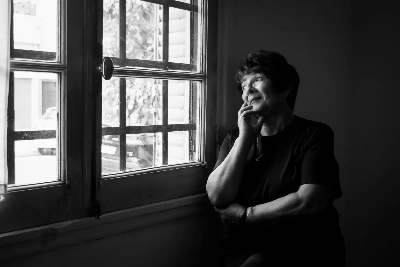 Femme pensive assise près d'une fenêtre, regard tourné vers l'extérieur