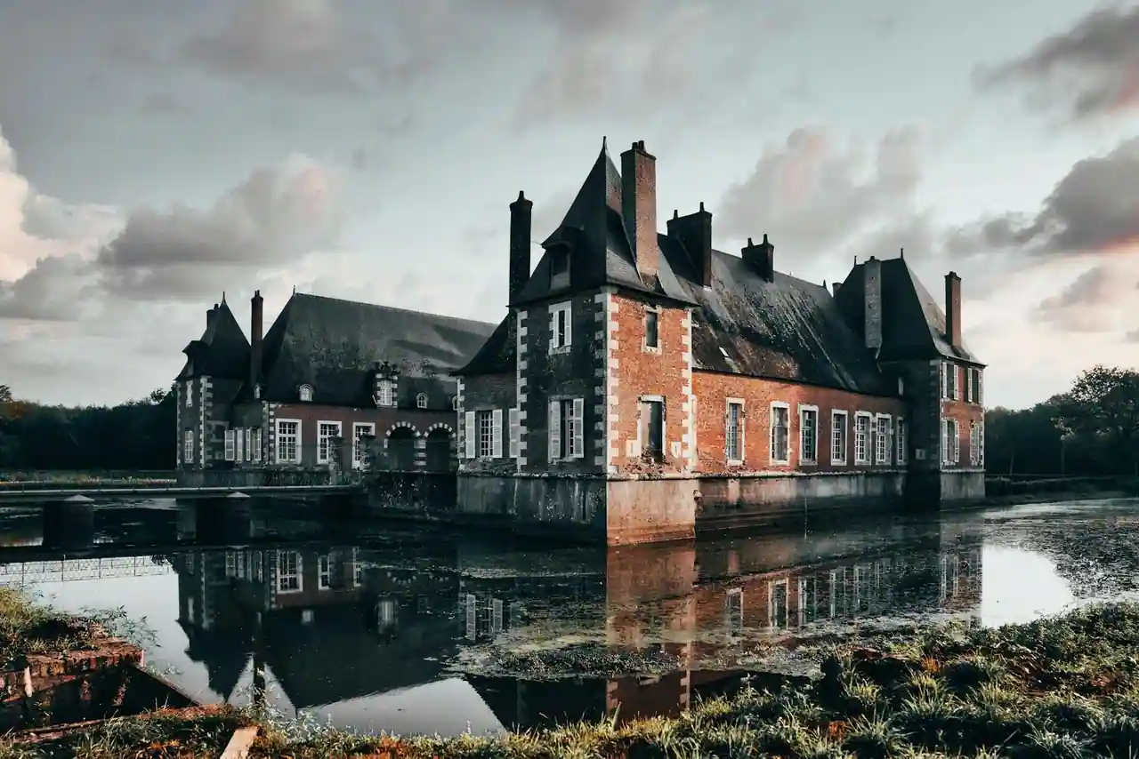 Château Renaissance en pierre se reflétant dans un plan d'eau au crépuscule