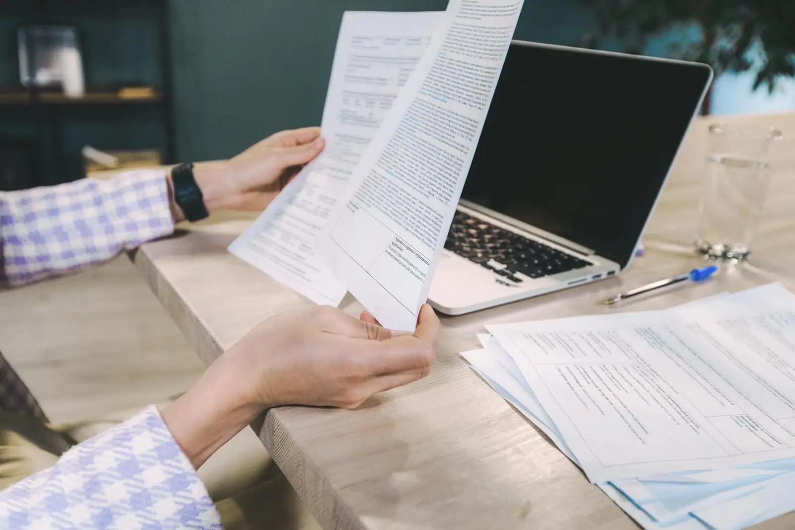 Personne relisant son CV sur un bureau avec un ordinateur portable et un carnet
