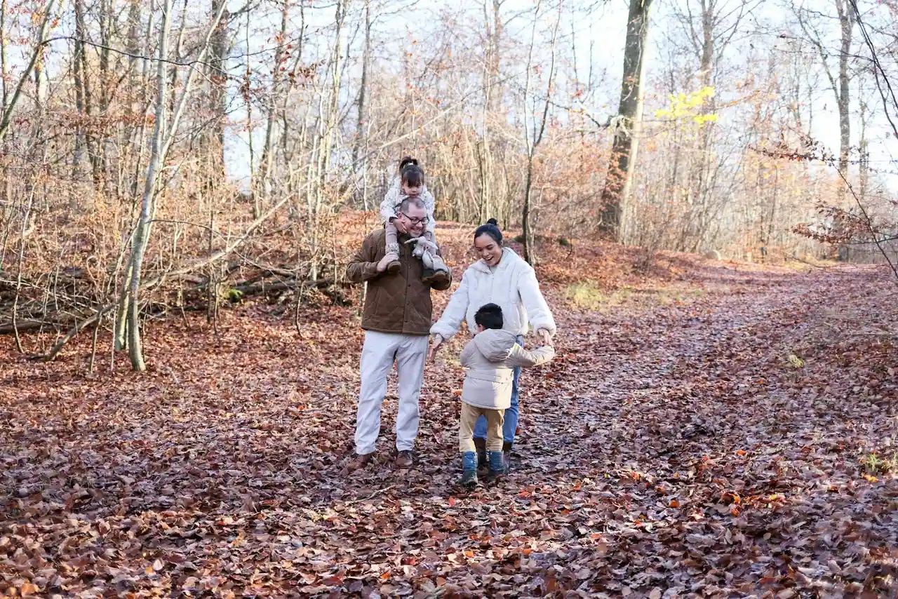 Parents et enfants marchant ensemble sur un sentier en forêt lors d'une sortie en famille gratuite en plein air.