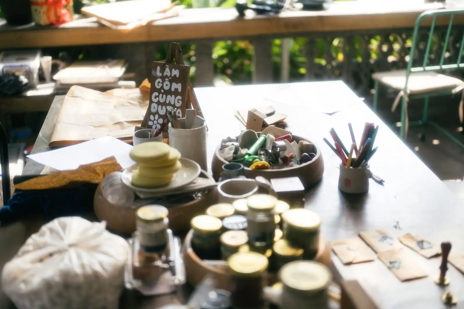 Table d'atelier de loisir créatif baignée de lumière, avec bols de matériel, pinceaux et petits pots