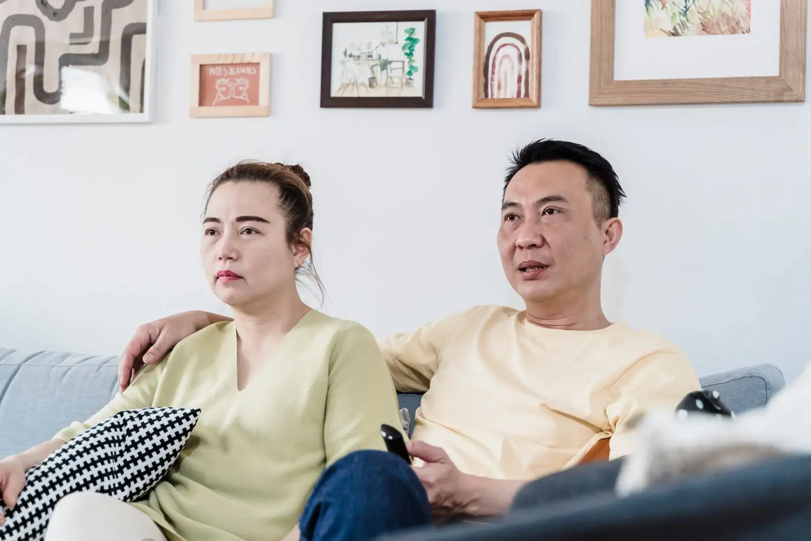 Un couple installé sur le canapé, télécommande en main, devant la télévision