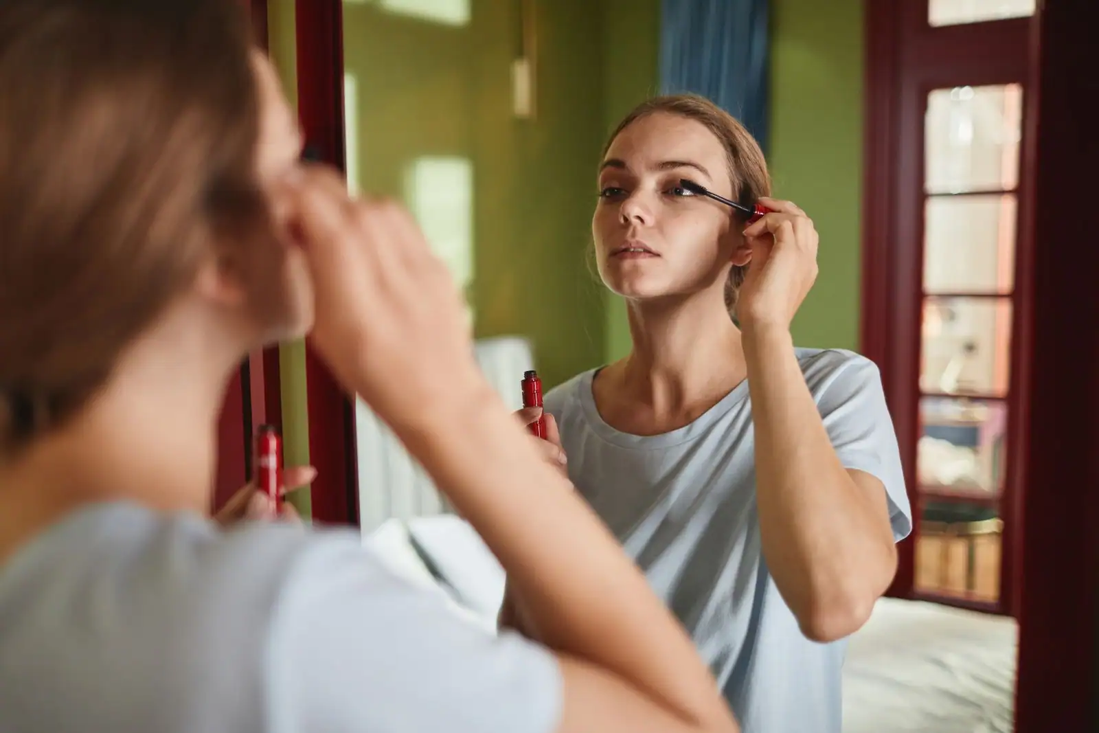 Femme appliquant son mascara devant un miroir pour un maquillage naturel du quotidien