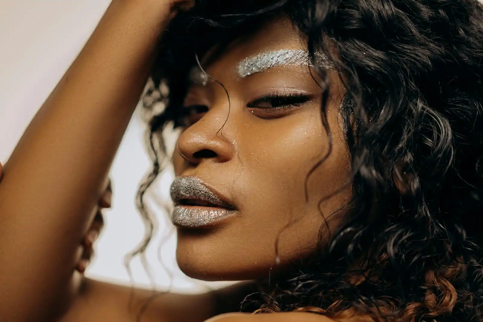 Portrait beauté d'une femme au maquillage scintillant, paillettes argentées sur les sourcils et les lèvres