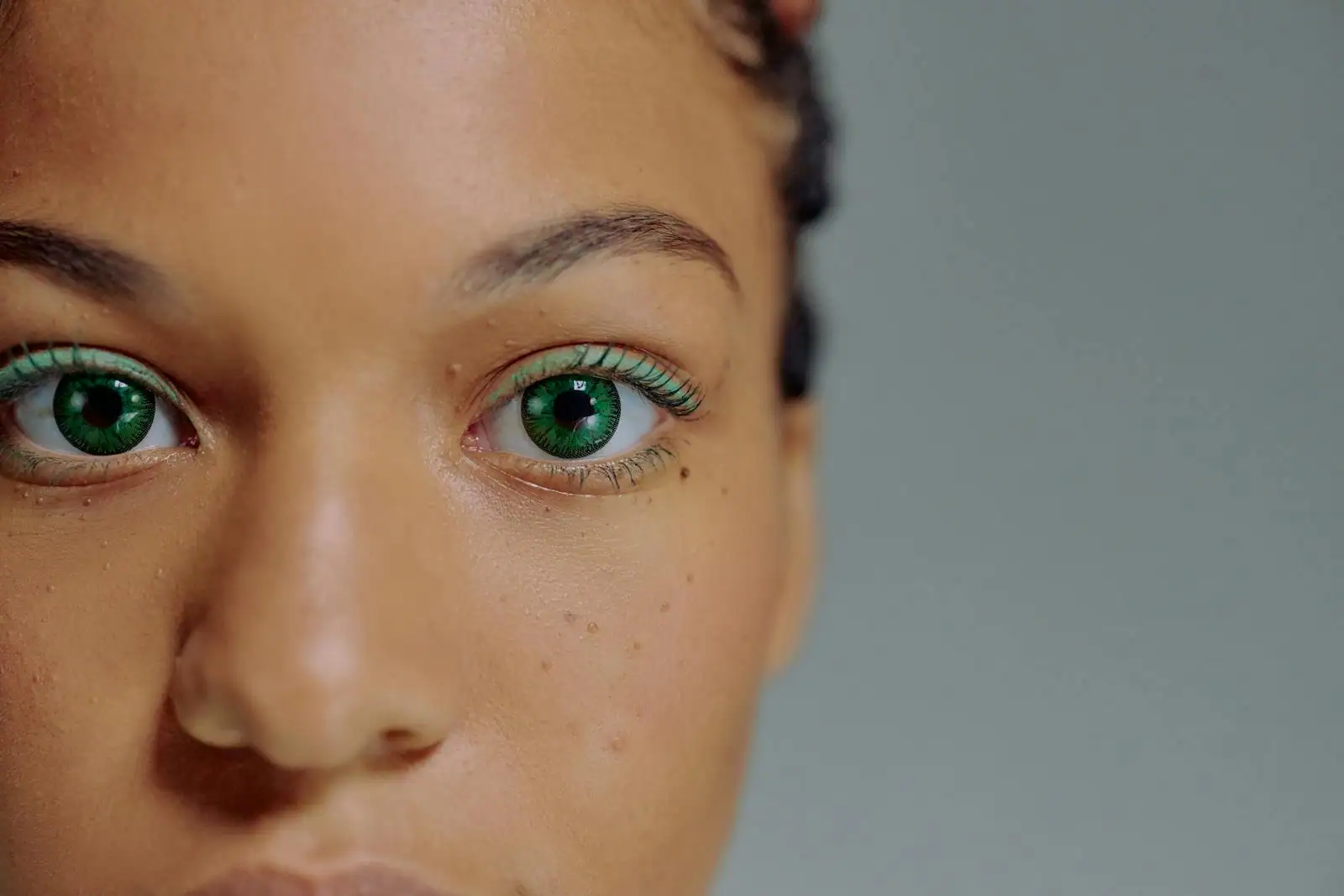 Gros plan sur le regard d'une femme aux yeux verts soulignés d'un maquillage des cils