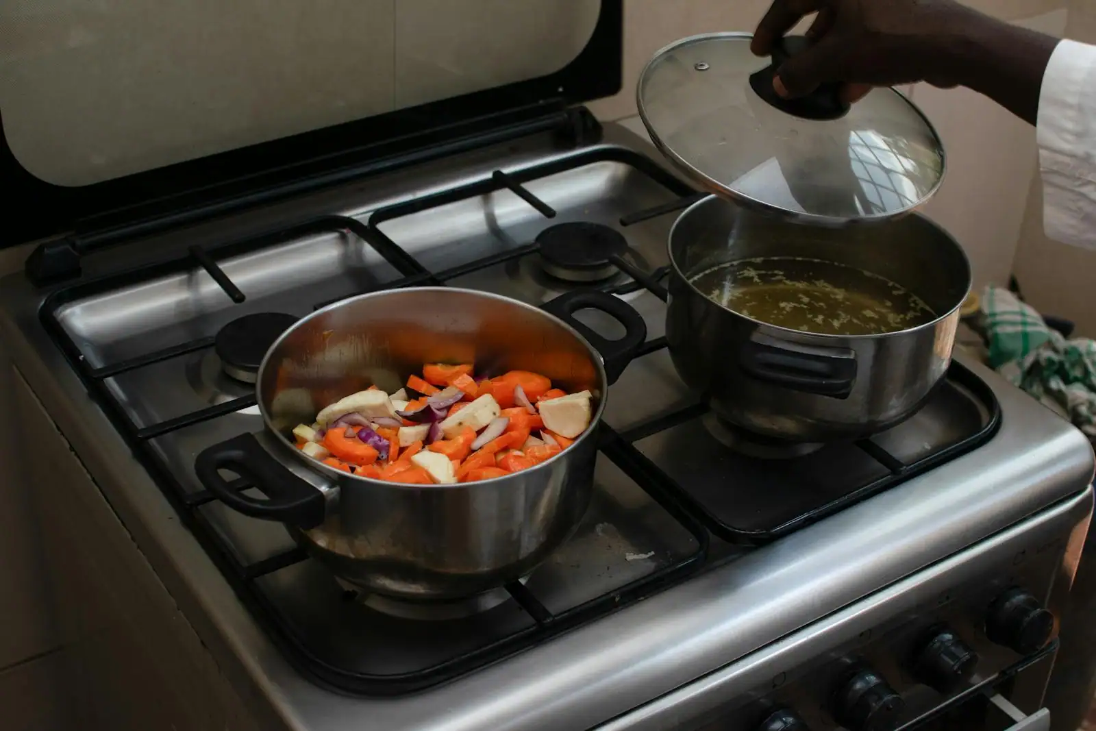 Mains préparant un plat mijoté traditionnel sur une cuisinière, dans une cuisine familiale