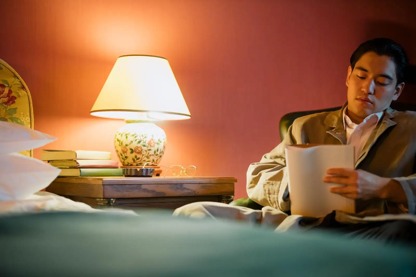 Personne lisant un carnet au lit, dans la lumière chaude d'une lampe de chevet