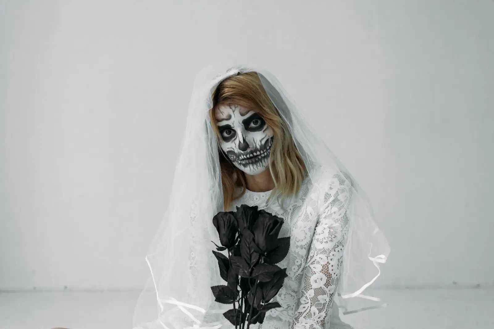 Femme maquillée en squelette pour Halloween, visage peint en blanc, orbites noircies et dents dessinées