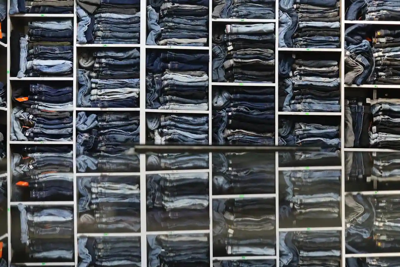 Vestiaire masculin soigné : chemises, pulls et pantalons aux tons neutres rangés sur une penderie.