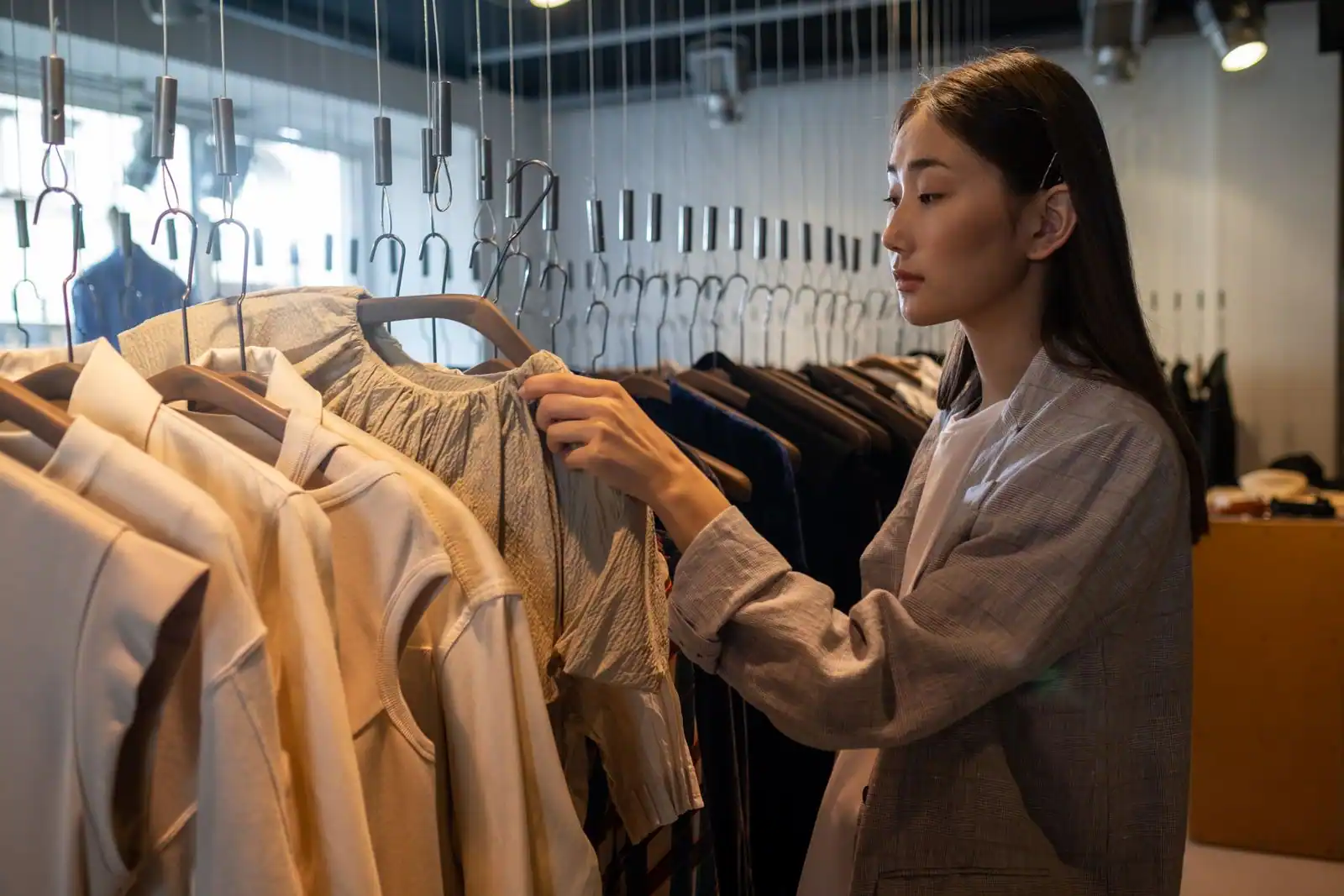 Femme choisissant un vêtement sur un portant dans une boutique de mode