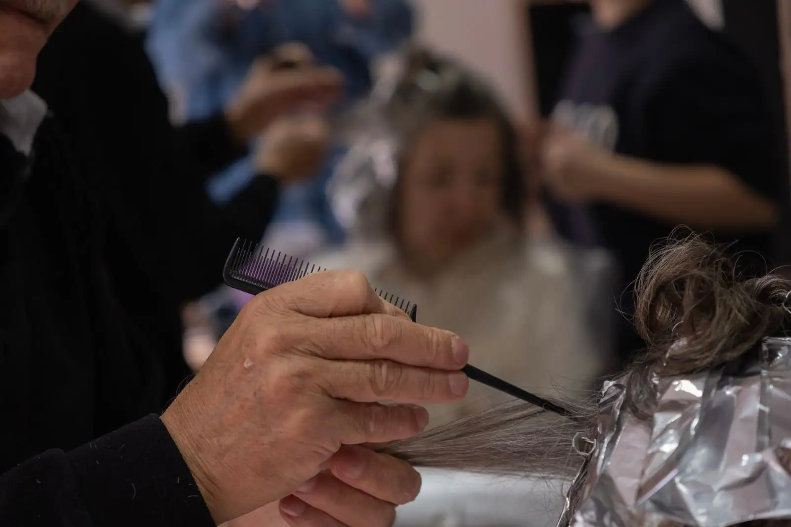 Application de mèches en papillotes chez le coiffeur, technique qui limite le contact du produit avec le cuir chevelu