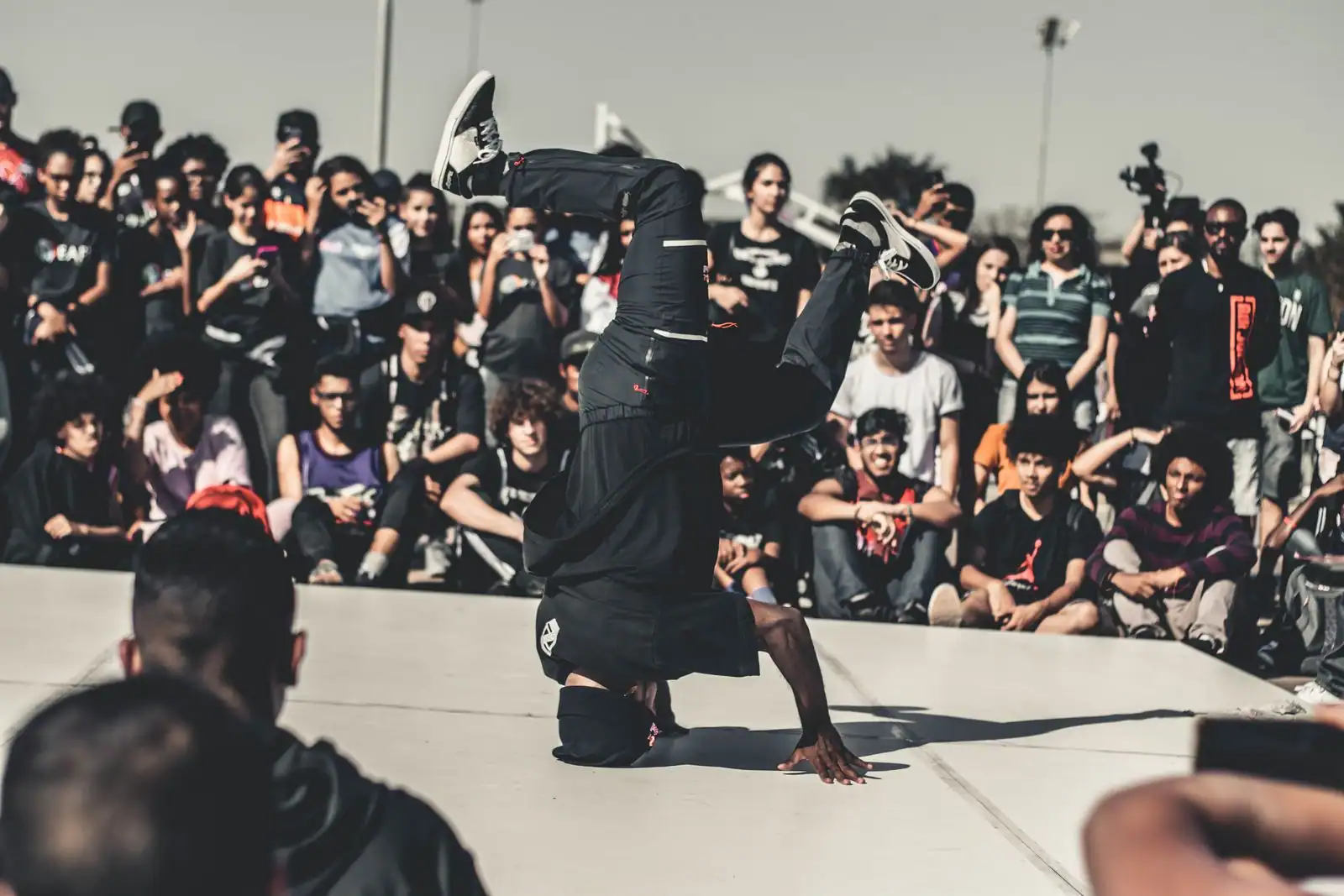 Danseur de rue en plein mouvement lors d'un festival de culture urbaine, public tout autour.