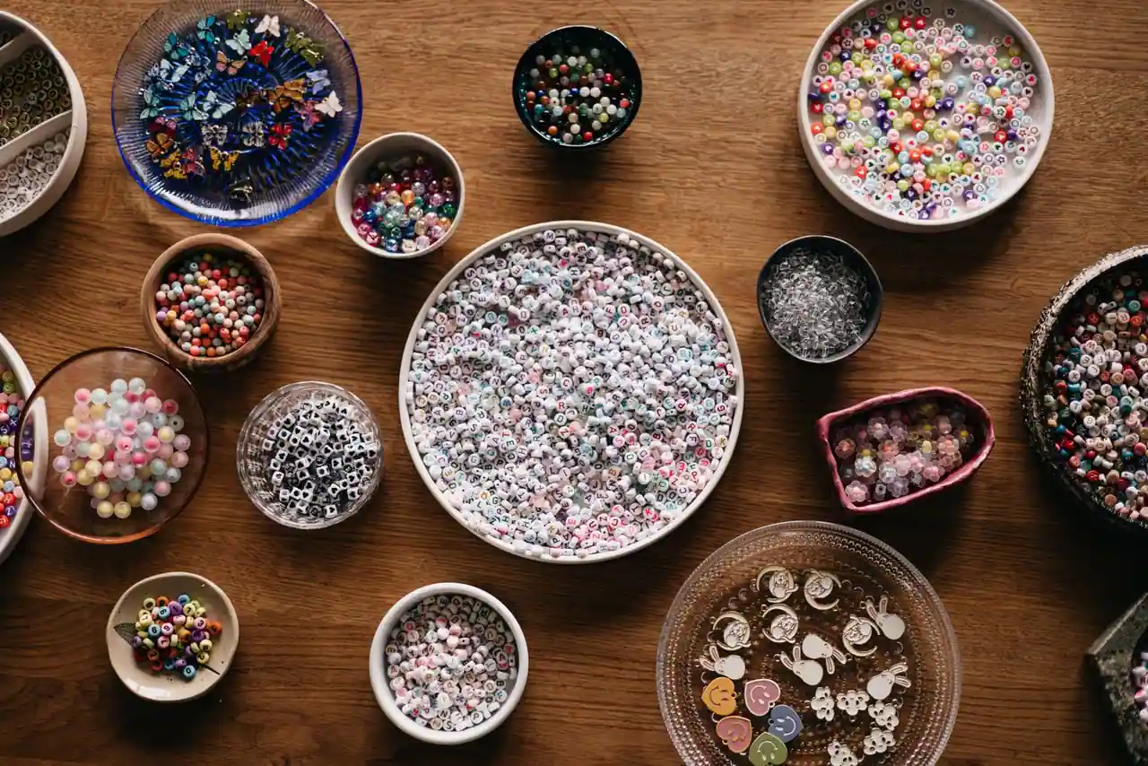 Perles colorées, dont des perles alphabet, réparties dans des coupelles sur une table en bois
