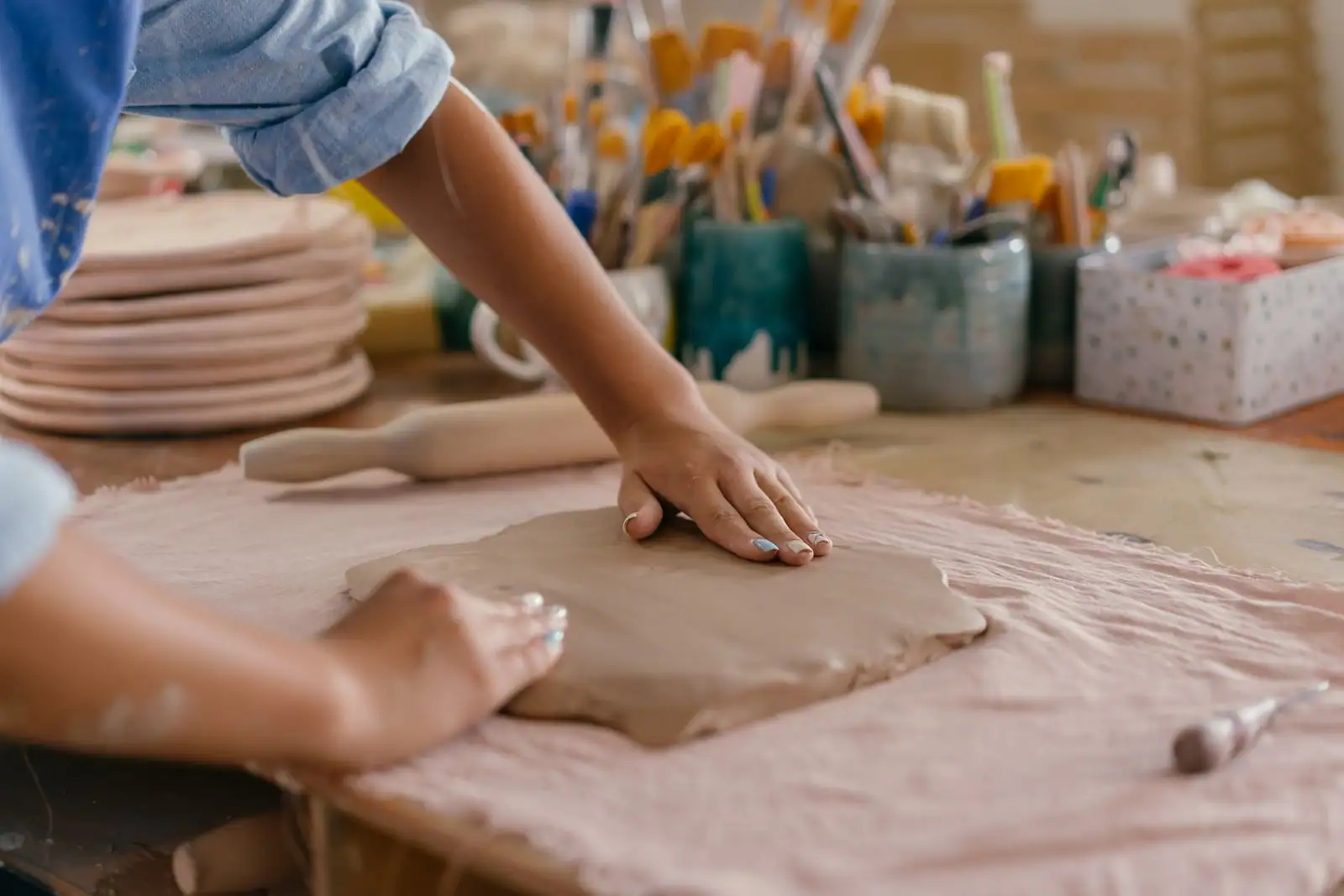 Mains d'un adulte façonnant une plaque d'argile dans un atelier de poterie, un loisir créatif