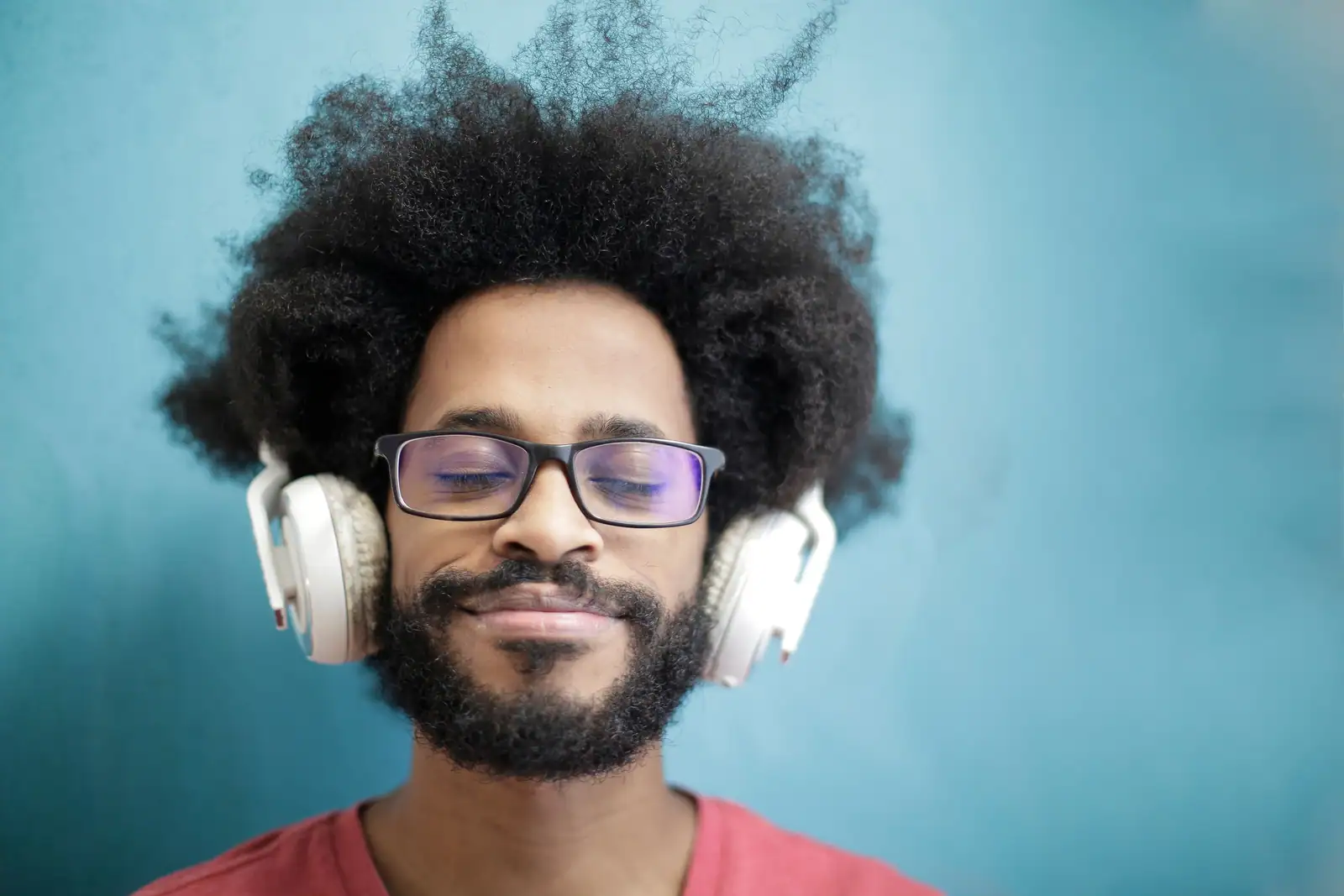 Homme au casque audio blanc, les yeux fermés et le visage détendu, absorbé par son écoute