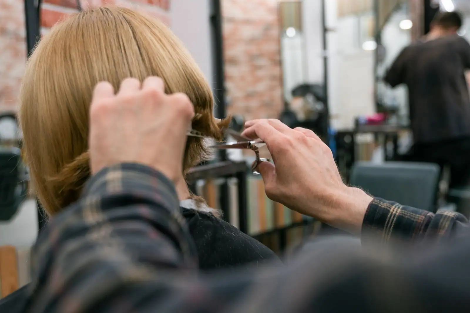 Coupe de cheveux réalisée aux ciseaux dans un salon de coiffure, vue de dos