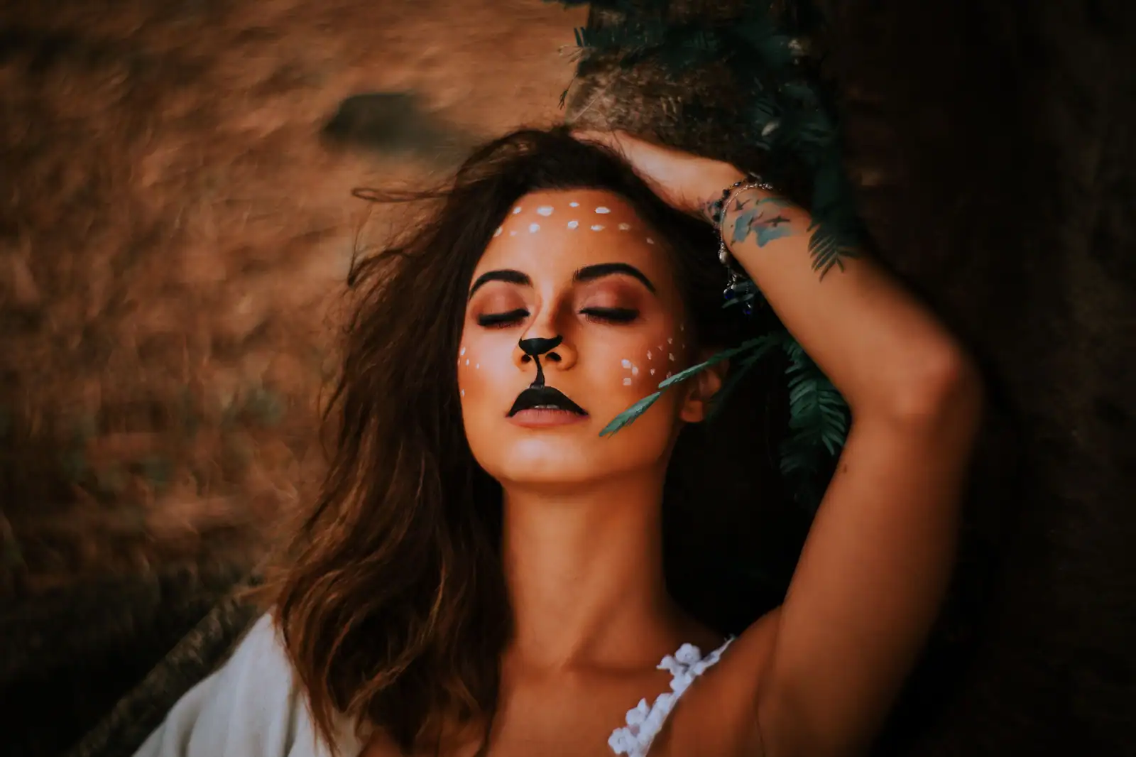Femme au maquillage de biche : truffe noire, trait vers la lèvre et taches blanches sur le visage