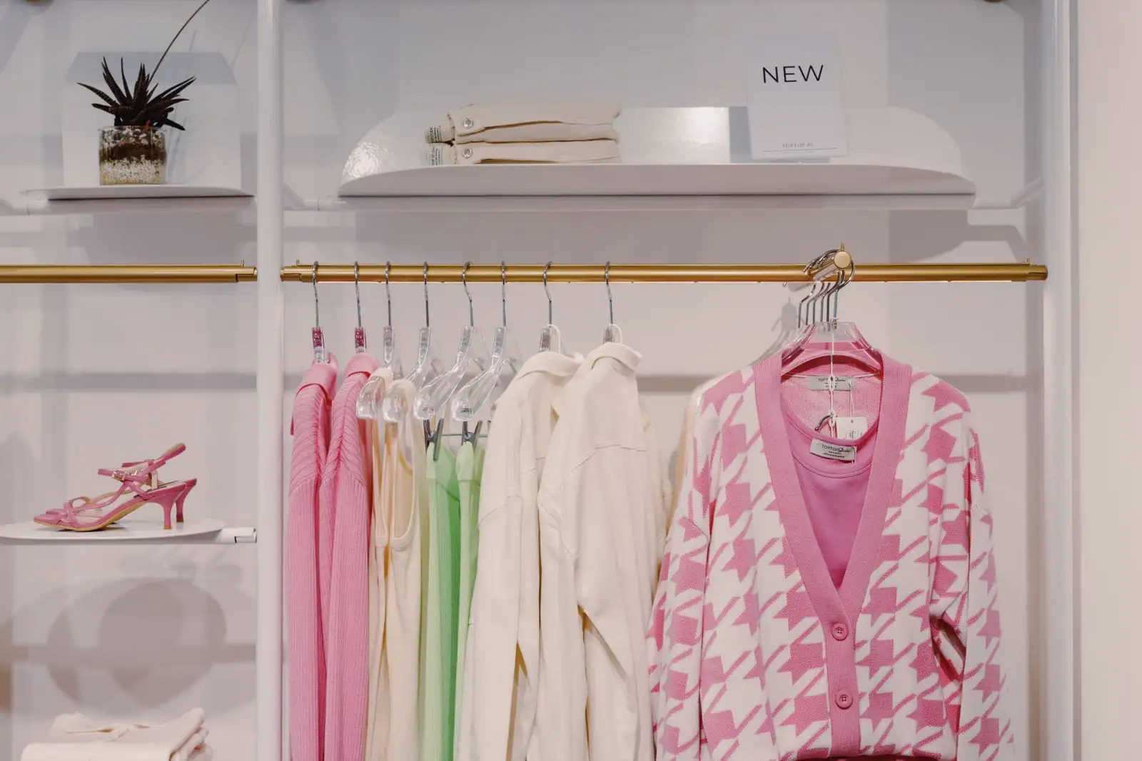 Intérieur d'une boutique de mode féminine, vêtements suspendus sur des portants dans un espace soigné.