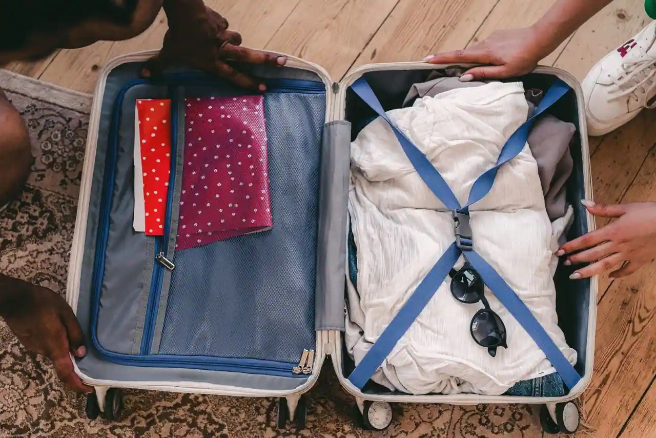 Valise ouverte remplie de vêtements pliés et maintenus par des sangles, prête pour le voyage.