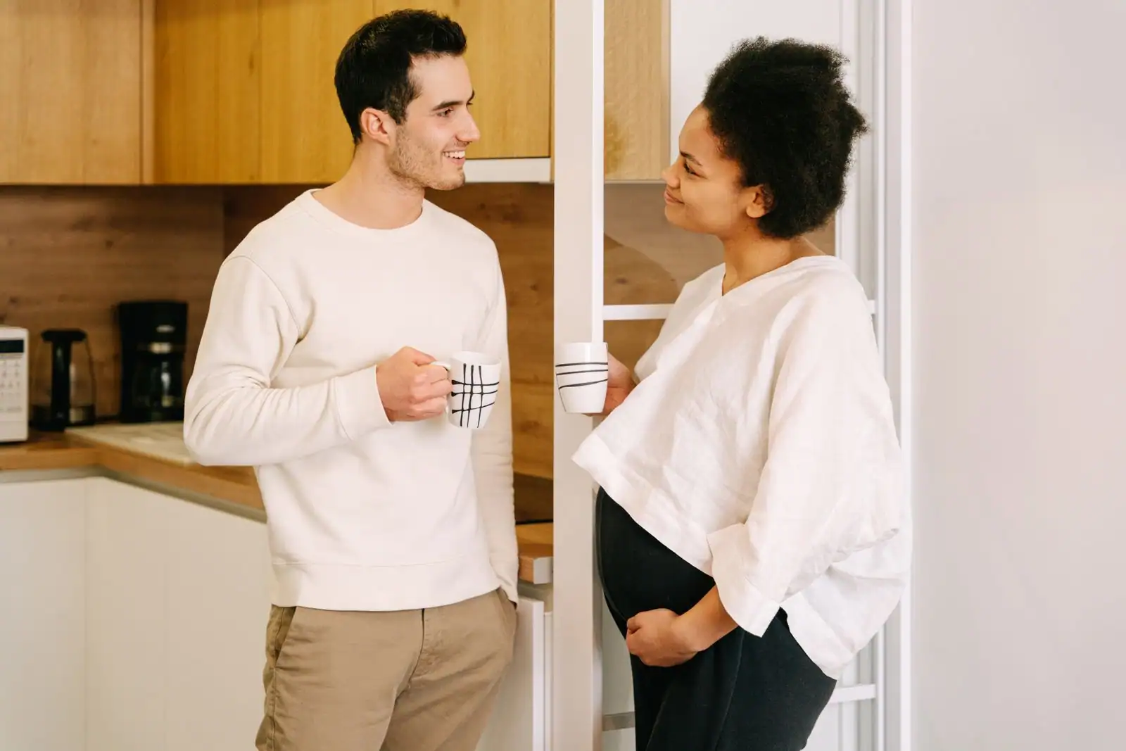 Couple complice en pleine conversation, assis face à face avec deux tasses