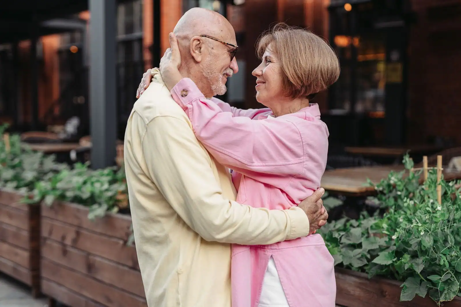 Couple souriant et enlacé en extérieur, illustrant la complicité et l’attachement au cœur d’une relation de couple.