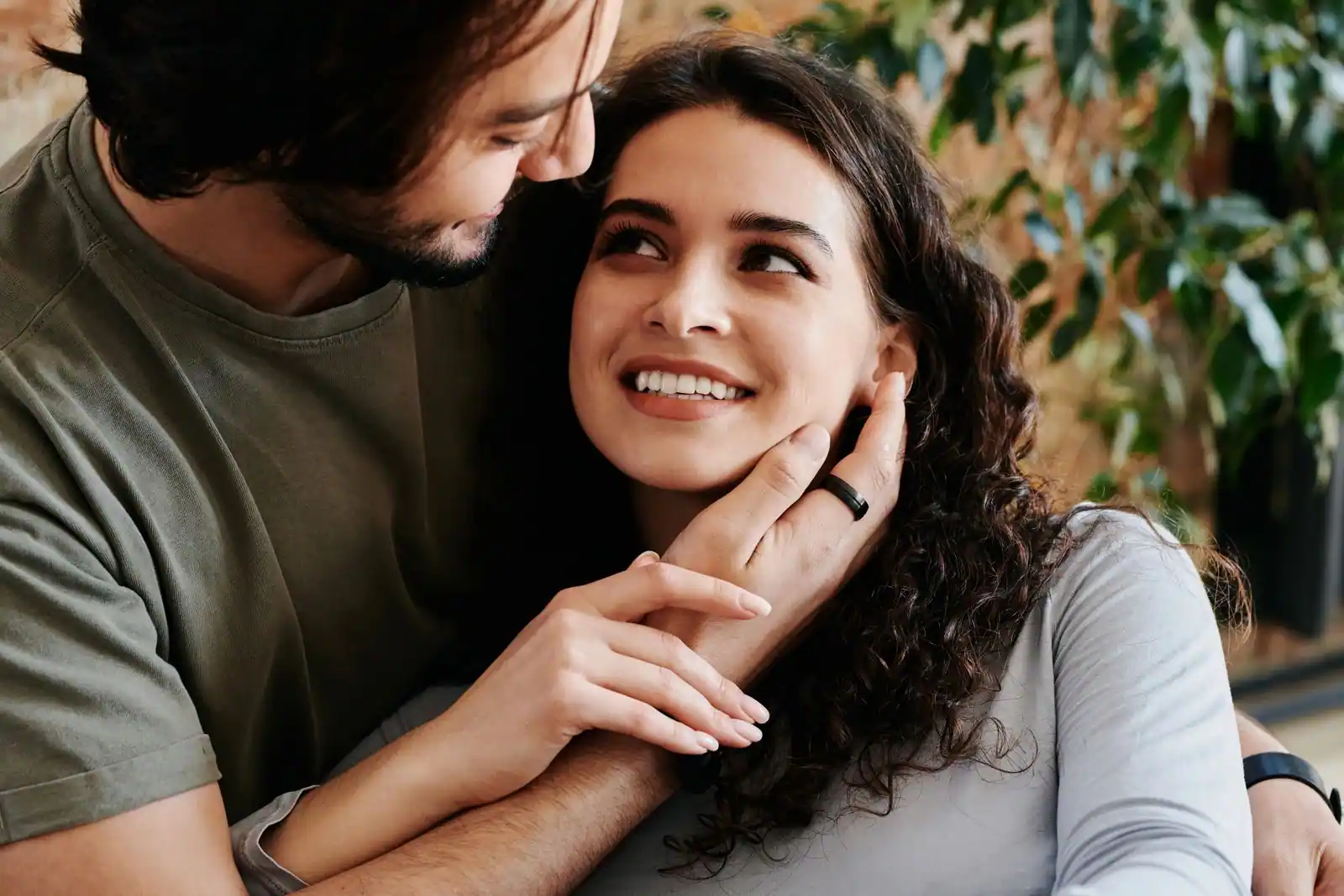 Couple enlacé et souriant, l'homme tenant tendrement le visage de sa compagne, moment complice