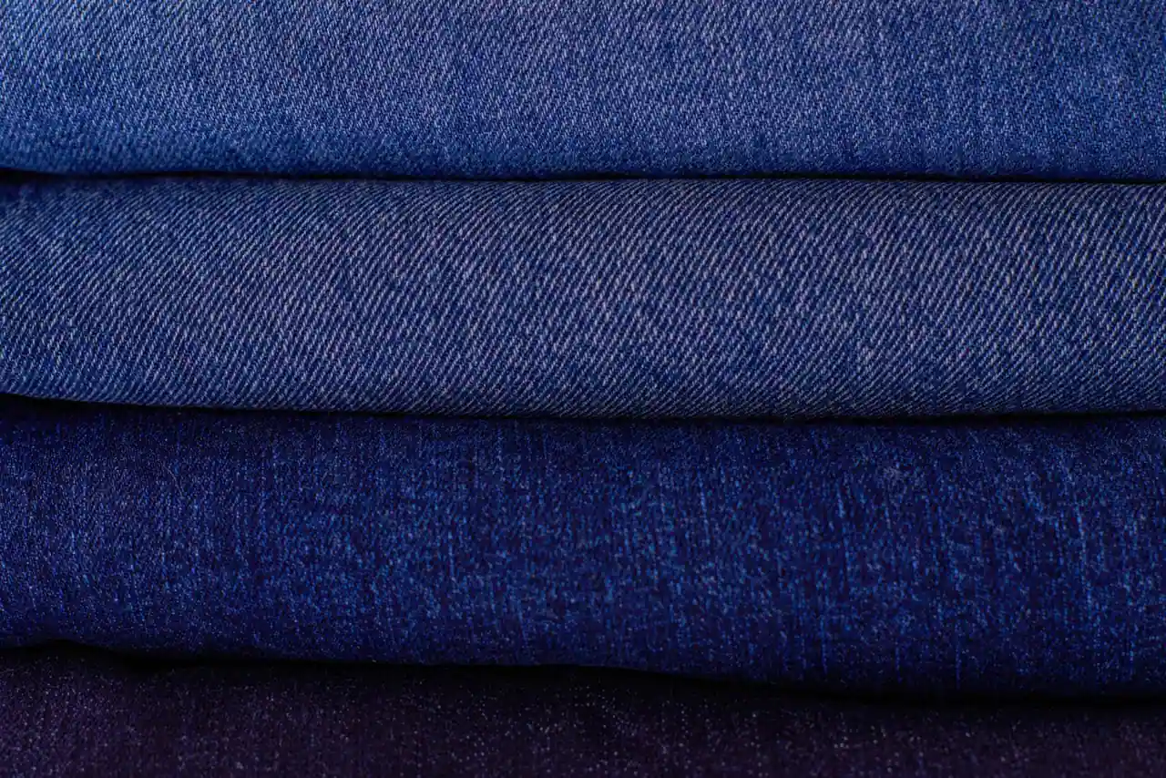 Pile de pantalons en jean bleu soigneusement pliés les uns sur les autres, en gros plan sur le denim
