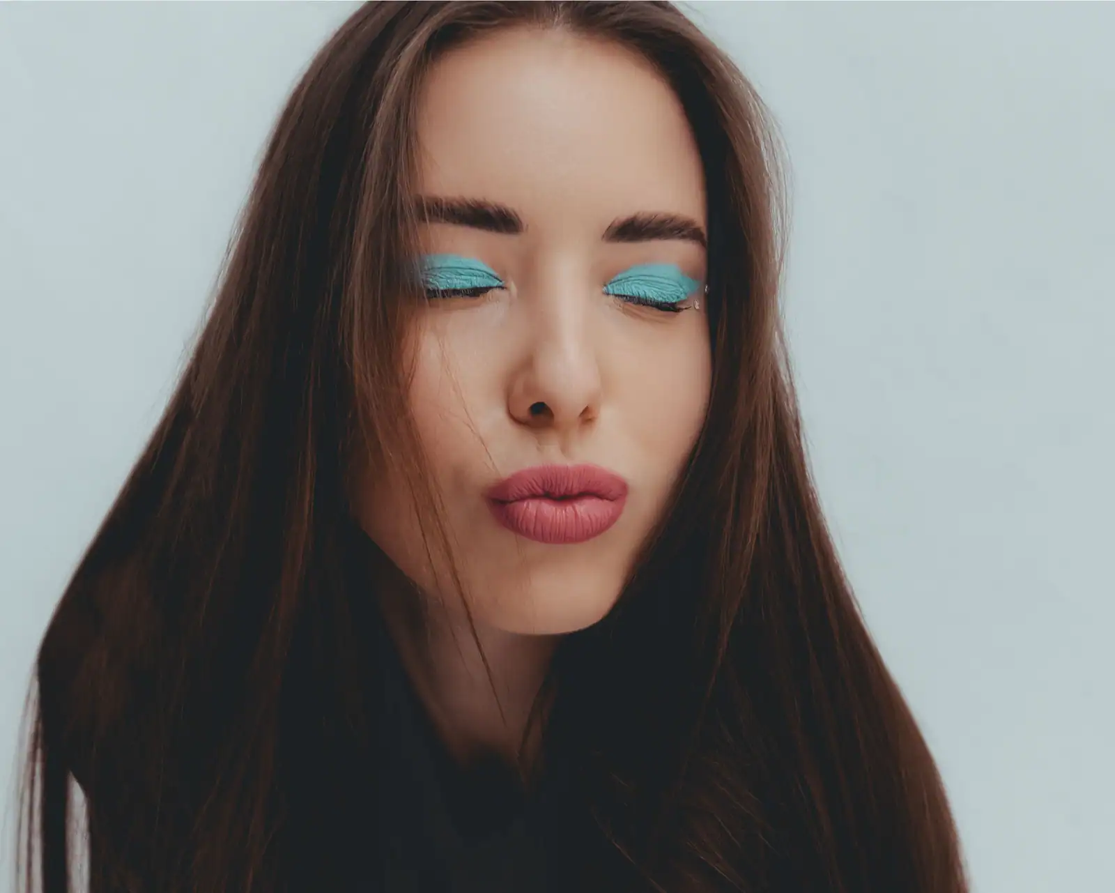 Paupières fardées de turquoise pastel en aplat, façon maquillage des années 2000, bouche rosée