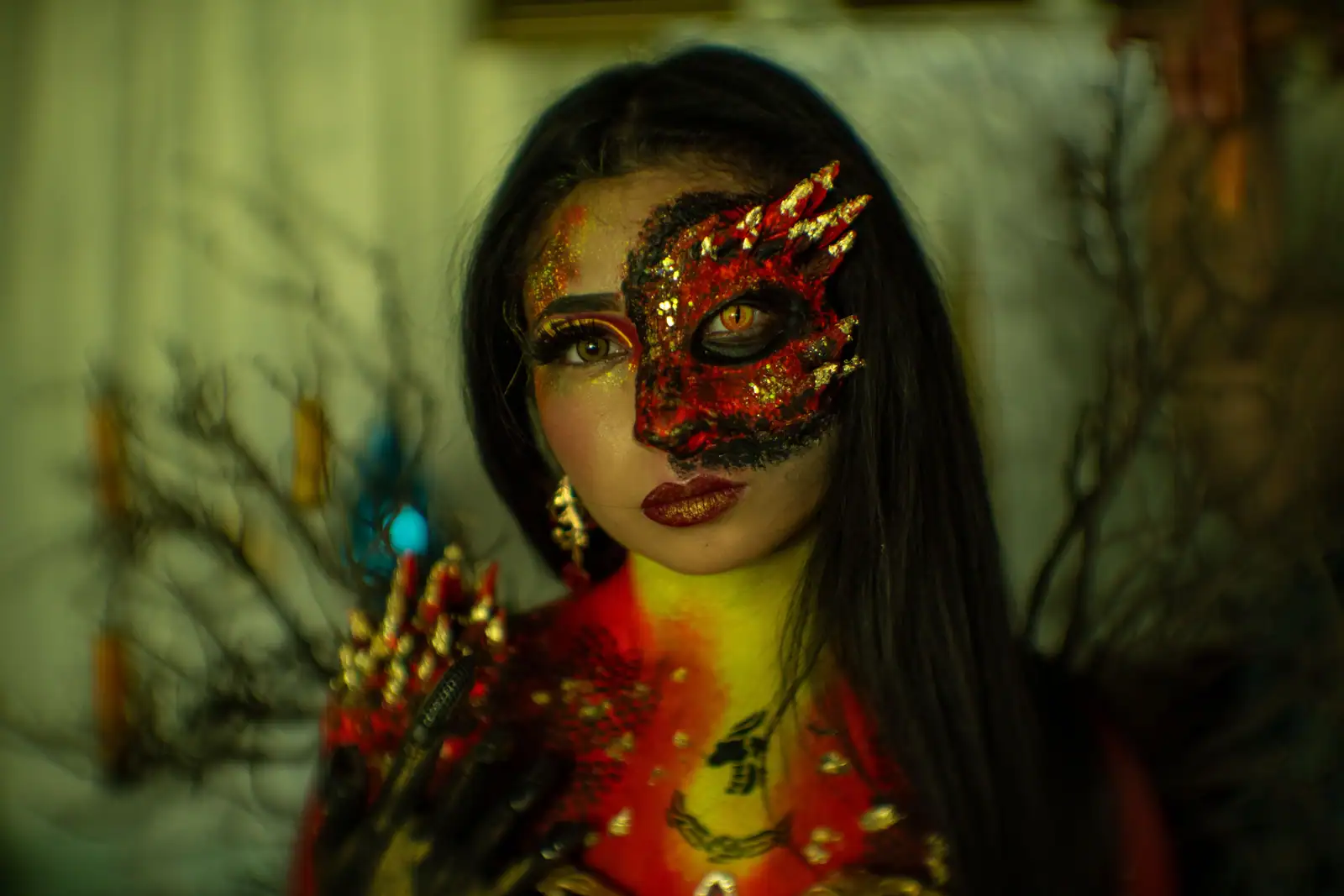 Maquillage de dragon rouge et or : écailles sur la moitié du visage et pointes peintes au-dessus de l'œil