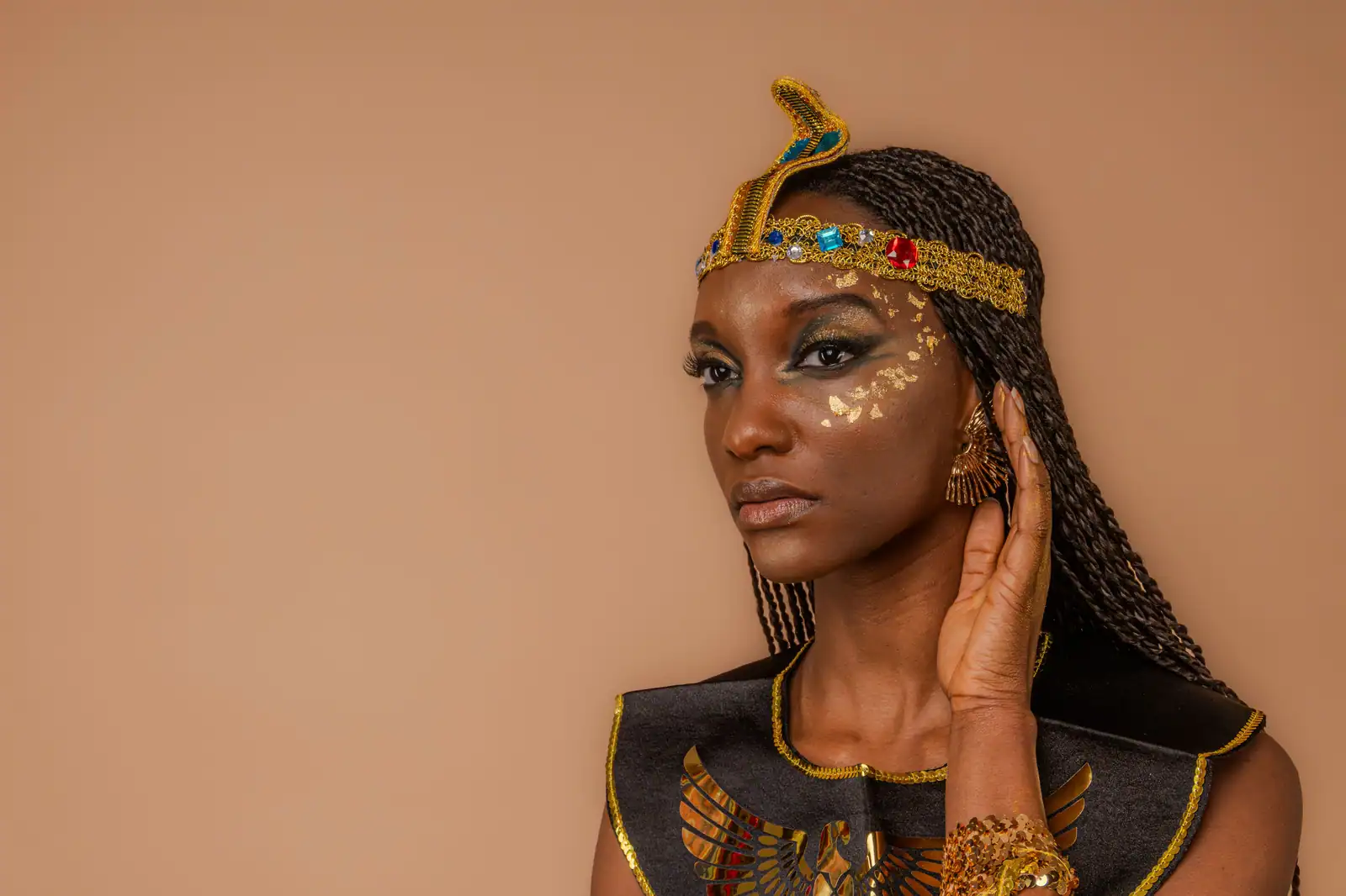 Femme en tenue d’inspiration égyptienne, l’œil souligné de noir et de vert, éclats dorés sur la pommette